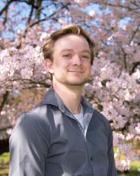 Photo of Erik in front of cherry blossoms. 
